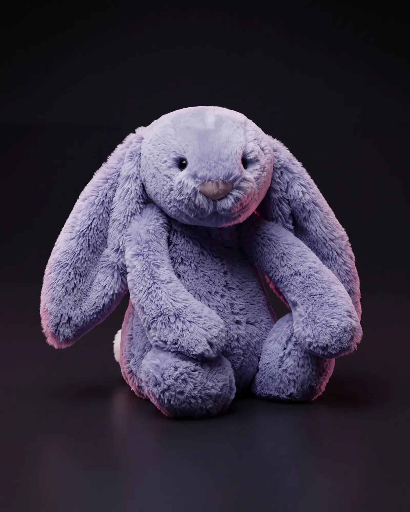 A violet-blue Jellycat Bashful Bunny with long floppy ears, on a dark studio sweep.