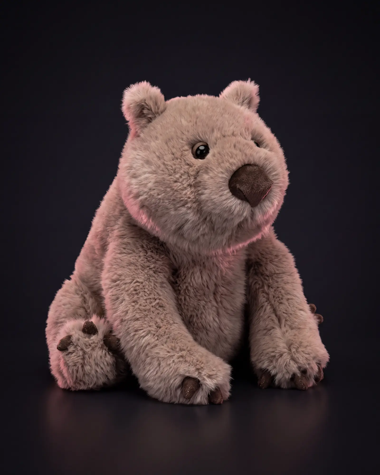 A taupe-grey Jellycat wombat sitting square on a dark studio sweep, lit with a pink rim light.